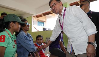Malaysian politician Anwar Ibrahim, right, greets voters at a polling station in the southern coastal town of Port Dickson, where Anwar is vying for a seat along with six other candidates, Saturday, Oct. 13, 2018. Voting opened Saturday in a by-election that is expected to see charismatic Malaysian politician Anwar Ibrahim win a parliamentary seat and return to active politics as he prepare for his eventual takeover from Prime Minister Mahathir Mohamad. (AP Photo/Vincent Thian)