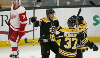 Boston Bruins right wing David Pastrnak celebrates his third goal of an NHL hockey game with teammates Patrice Bergeron (37) and Brad Marchand as Detroit Red Wings defenseman Nick Jensen (3) skates by during the third period Saturday, Oct. 13, 2018, in Boston. (AP Photo/Mary Schwalm)