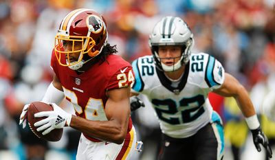 Washington Redskins cornerback Josh Norman (24) carries the ball after pulling in an interception as Carolina Panthers running back Christian McCaffrey (22) pursues him during the first half of an NFL football game, Sunday, Oct. 14, 2018, in Landover, Md. (AP Photo/Patrick Semansky)