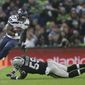 Seattle Seahawks running back Mike Davis (27), left, escapes the clutches of Oakland Raiders linebacker Tahir Whitehead (59) during the first half of an NFL football game at Wembley stadium in London, Sunday, Oct. 14, 2018. (AP Photo/Tim Ireland)