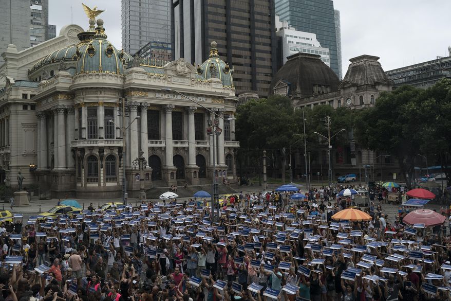 People hold street signs honoring slain councilwoman Marielle Franco as they mark the 7th month since her murder in Rio de Janeiro, Brazil, Sunday, Oct. 14, 2018. Franco supporters distributed a thousand street signs in memory of her after a video on social media showed one being destroyed by two politicians with the right wing Social Liberal Party. (AP Photo/Leo Correa)