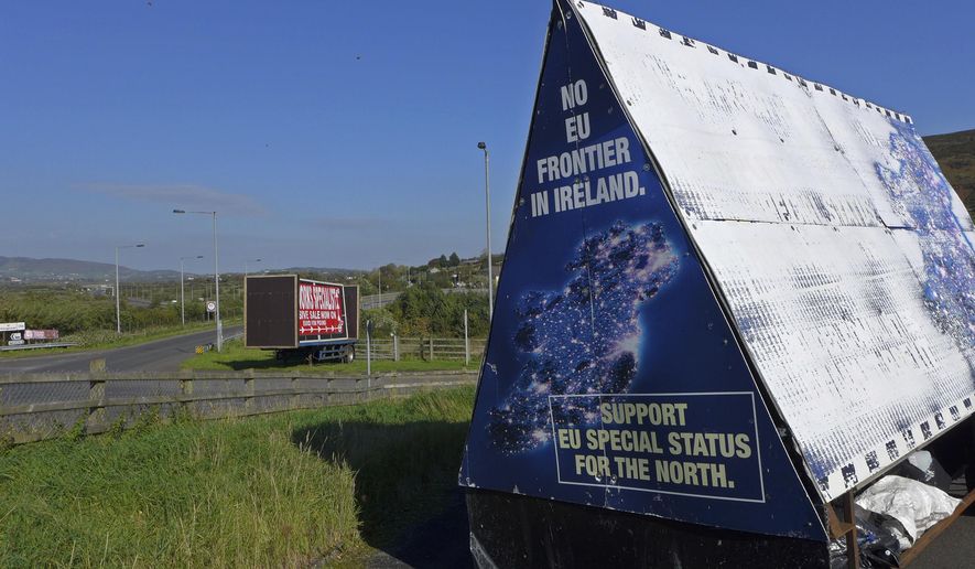 In this photo taken on Wednesday, Oct. 10, 2018, a sign in a parking lot of a cemetery reads: &amp;quot;No EU border in Ireland&amp;quot; near Carrickcarnan, Ireland, just next to the Jonesborough Parish church in Northern Ireland. The land around the small town of Carrickcarnan, Ireland is the kind of place where Britain’s plan to leave the European Union walks right into a wall - an invisible one that is proving insanely difficult to overcome. Somehow, a border of sorts will have to be drawn between Northern Ireland, which is part of the United Kingdom, and EU member country Ireland to allow customs control over goods, produce and livestock once the U.K. has left the bloc. (AP Photo/Lorne Cook)