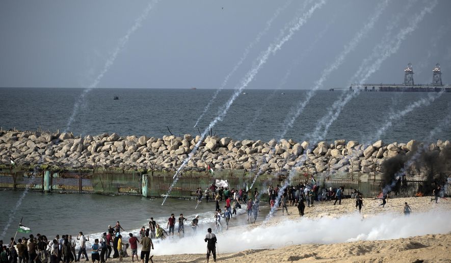 Teargas canisters fired by Israeli troops fall over Palestinians during a protest on the beach at the border with Israel near Beit Lahiya, northern Gaza Strip, Monday, Oct. 15, 2018.(AP Photo/Khalil Hamra)