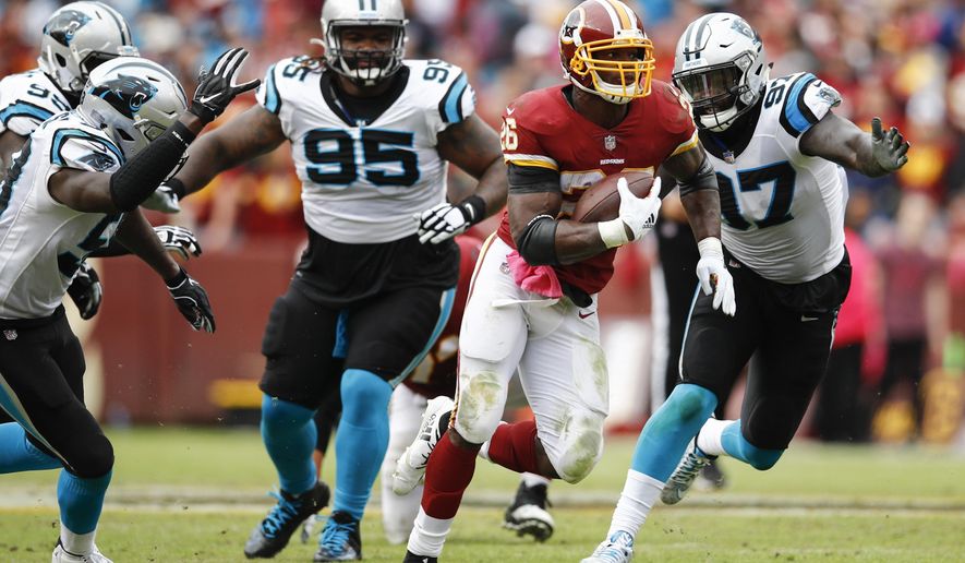 Washington Redskins running back Adrian Peterson (26) carries the ball past Carolina Panthers nose tackle Dontari Poe (95) and defensive end Mario Addison (97) during the second half of an NFL football game, Sunday, Oct. 14, 2018, in Landover, Md. (AP Photo/Patrick Semansky)