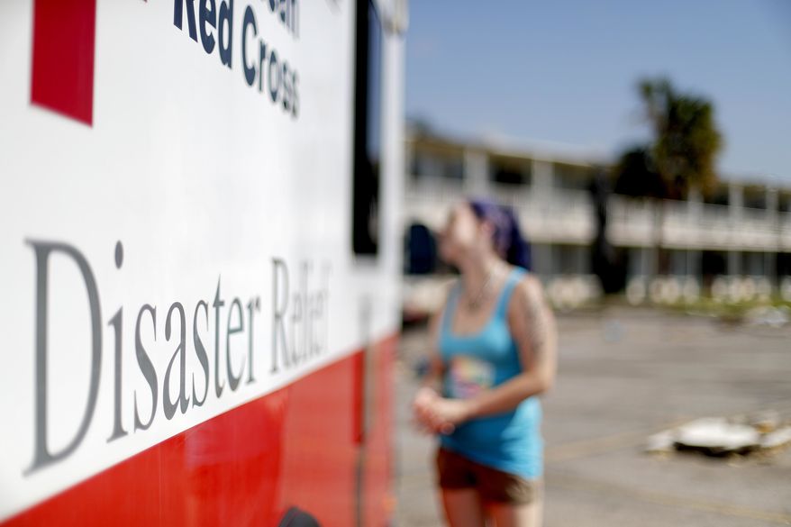 Crystal Williams receives food from the Red Cross outside a damaged motel, Tuesday, Oct. 16, 2018, in Panama City, Fla., where many residents continue to live in the aftermath of Hurricane Michael. (AP Photo/David Goldman)