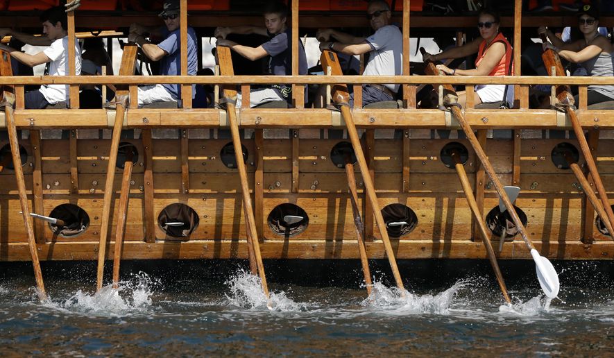 In this Sunday, Sept. 16, 2018 photo, visitors row the Olympias, replica of an ancient galley, at Saronic gulf in southern Athens. The 37-meter (121-foot) wooden vessel moored off southern Athens is an experimental reconstruction of the trireme, the sleek ancient Greek warship that halted a Persian invasion of Europe and ruled the Mediterranean for centuries.Every summer, visitors can get a whiff of life in the galleys 2,500 years ago by joining the crew of the Olympias, and work up a sweat rowing it. (AP Photo/Thanassis Stavrakis)