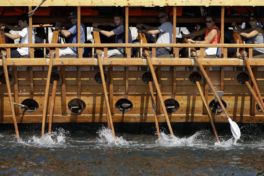 In this Sunday, Sept. 16, 2018 photo, visitors row the Olympias, replica of an ancient galley, at Saronic gulf in southern Athens. The 37-meter (121-foot) wooden vessel moored off southern Athens is an experimental reconstruction of the trireme, the sleek ancient Greek warship that halted a Persian invasion of Europe and ruled the Mediterranean for centuries.Every summer, visitors can get a whiff of life in the galleys 2,500 years ago by joining the crew of the Olympias, and work up a sweat rowing it. (AP Photo/Thanassis Stavrakis)