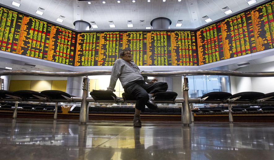 An investor sits at private stock trading boards at a private stock market gallery in Kuala Lumpur, Malaysia, Tuesday, Oct. 16, 2018. Asian markets were mostly higher on Tuesday, though Chinese benchmarks fell after the government reported inflation rose for the fourth straight month. (AP Photo/Yam G-Jun)