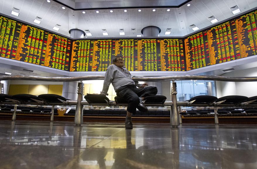 An investor sits at private stock trading boards at a private stock market gallery in Kuala Lumpur, Malaysia, Tuesday, Oct. 16, 2018. Asian markets were mostly higher on Tuesday, though Chinese benchmarks fell after the government reported inflation rose for the fourth straight month. (AP Photo/Yam G-Jun)