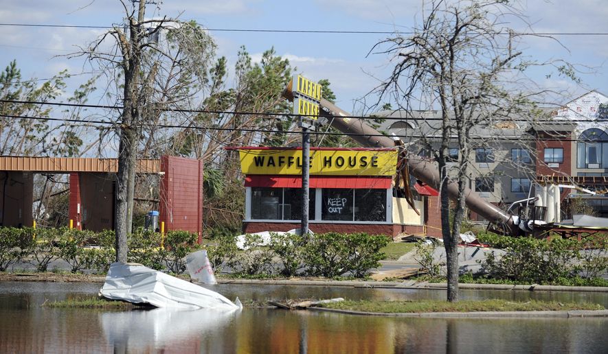 In this Sunday, Oct. 14, 2018, photo, a billboard lies atop a Waffle House restaurant after being knocked down by Hurricane Michael, in Panama City, Fla. (Carlos R. Munoz/Sarasota Herald-Tribune via AP)