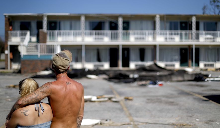 Residents line up for food from the Red Cross outside a damaged motel, Tuesday, Oct. 16, 2018, in Panama City, Fla., where many residents continue to live in the aftermath of Hurricane Michael. Some residents rode out the storm and have no place to go even though many of the rooms at the motel are uninhabitable. (AP Photo/David Goldman)