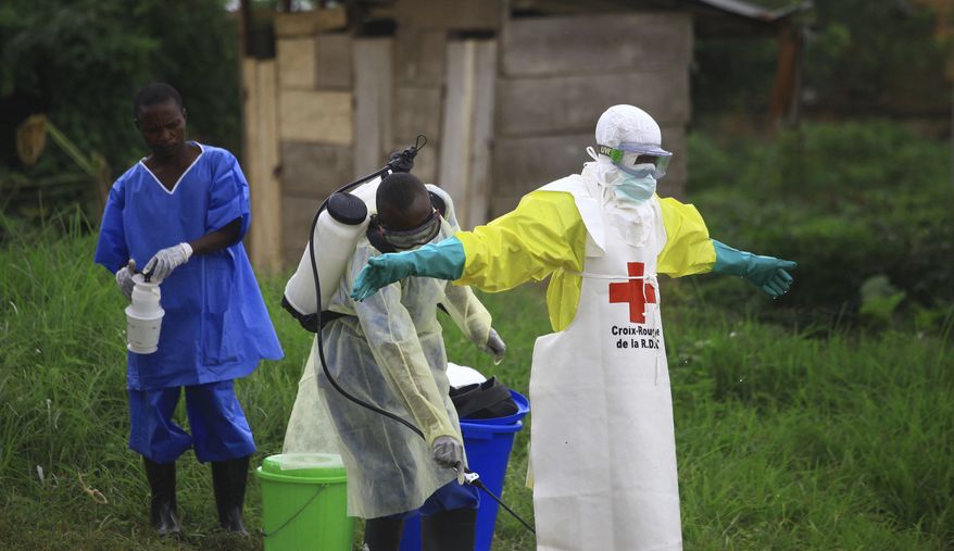 In this Sunday, Sept 9, 2018, photo, a health worker sprays disinfectant on his colleague after working at an Ebola treatment center in Beni, Eastern Congo. (AP Photo/Al-hadji Kudra Maliro) ** FILE **