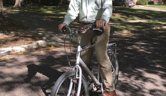 In this Oct. 17, 2018 photo provided by Marjorie Sable, George Smith, professor emeritus at the University of Missouri who won the 2018 Nobel Prize for chemistry. rides his bike on a biking/walking trail in Columbia, Mo. The university is honoring its Nobel Prize-winning scientist with an unusual accolade: a dedicated bicycle rack slot. It will be a standard bike rack, the same as those used by other bicyclists on campus. But the university plans to post a sign letting everyone know that this particular space belongs to a Nobel laureate. (Marjorie Sable photo via AP)