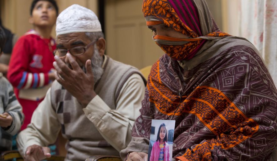 In this Jan. 18, 2018, file photo, Nusrat holds a picture of her daughter Zainab Ansari with her husband Mohammed Amin Ansari, left, in Kasur, Pakistan. Mohammad Imran, a serial killer of eight children, was executed at a Pakistani prison Wednesday morning, Oct. 17, 2018, after the country's top court rejected a request for his public hanging, officials said. Zainab's father Mohammed Amin Ansari was specially allowed to witness the execution. (AP Photo/B.K. Bangash, File)