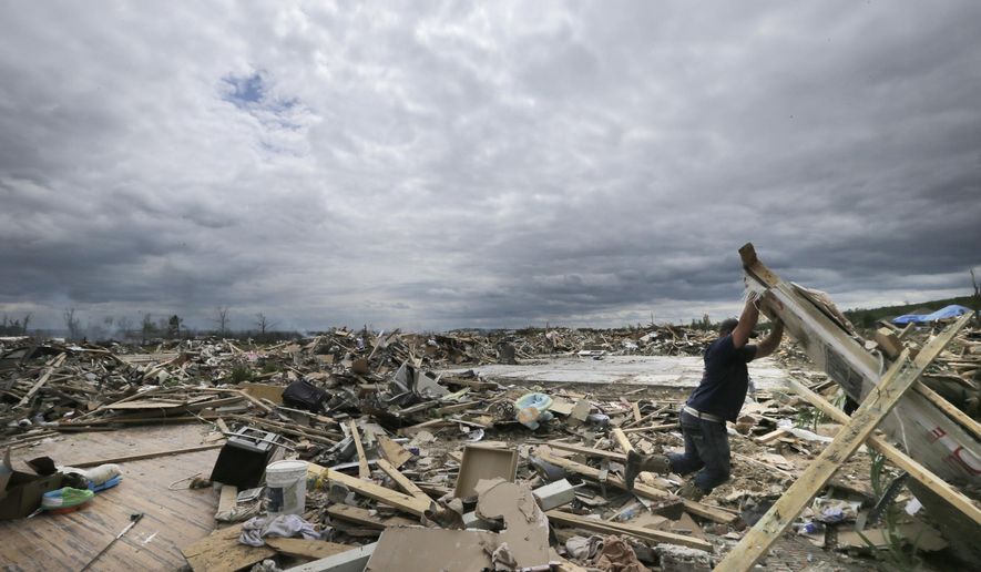 FILE - In this April 30, 2014, file photo, Dustin Shaw lifts debris as he searches through what is left of his sister's house at Parkwood Meadows neighborhood after a tornado in Vilonia, Ark. A new study finds that tornado activity is generally shifting eastward to areas just east of the Mississippi River that are more vulnerable such as Mississippi, Arkansas and Tennessee. And it's going down in Oklahoma, Kansas and Texas. (AP Photo/Danny Johnston, File)
