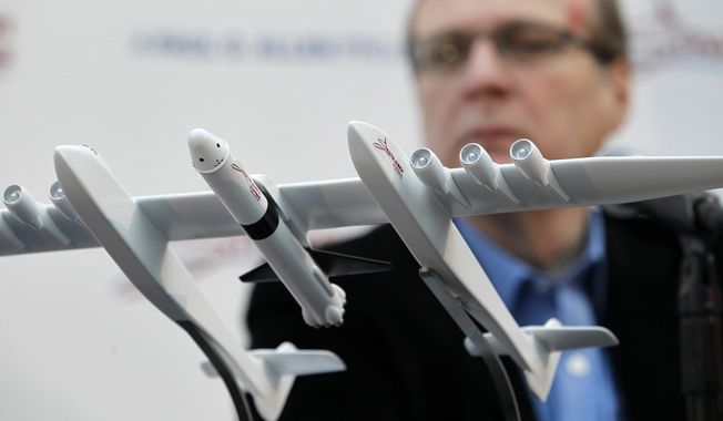FILE- In this Dec. 13, 2011, file photo Microsoft co-founder Paul Allen looks across at a model of a giant airplane and spaceship he plans on building, during a news conference about the plane in Seattle. Prior to his death on Monday, Oct. 15, 2018, Allen invested large sums in technology ventures, research projects and philanthropies, some of them eclectic and highly speculative. Outside of bland assurances from his investment company, no one seems quite sure what happens now. (AP Photo/Elaine Thompson, File)