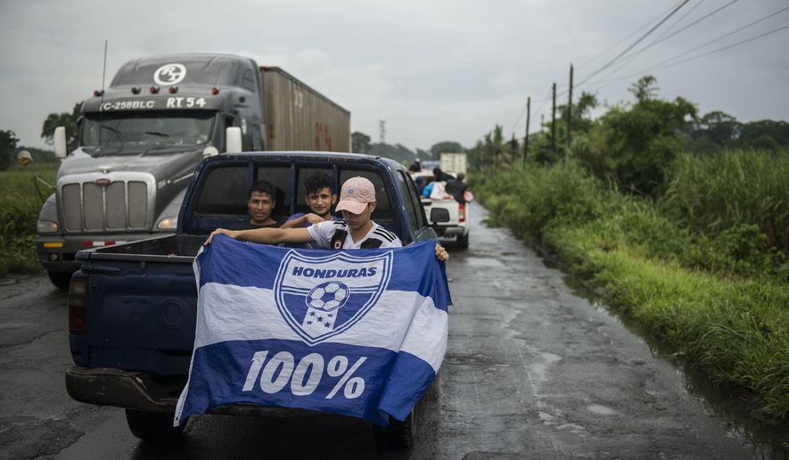 A Honduran migrant holds a Honduras national flag, as he sits in the bed of a  a pick-up truck, on his way to the Mexican border, in Cocales, about 80 miles north-west from Guatemala City, Guatemala, Thursday, Oct. 18, 2018. Many of the more than 2,000 Hondurans in a migrant caravan trying to wend its way to the United States left spontaneously with little more than the clothes on their backs and what they could quickly throw into backpacks. (AP Photo/ Oliver de Ros)