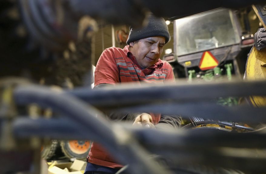 In this March 8, 2017, photo, provided by the Wisconsin Center for Investigative Journalism, Roberto Tecpile, a Mexican employee at Rosenholm farm in Cochrane, Wis., works in the machine shop fixing an alfalfa cropper. The owner of the dairy farm, John Rosenow, says his farm could not operate without immigrant labor, and claims none of the dairy farms in Wisconsin could continue to operate without relying on immigrants. Tecpile has been working for Rosenow's farm for the last four years, with hopes of returning to his family in Mexico in a year or two. (Coburn Dukehart/Wisconsin Center for Investigative Journalism via AP)