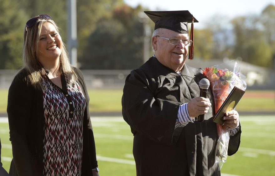 Michael Parker speaks to those in attendance after receiving his diploma from Scio School Board Vice Chairwoman Kerri Hyde, left, at Scio High School in Scio, Ore., Tuesday Oct. 16, 2018. (Mark Ylen/Albany Democrat-Herald via AP)