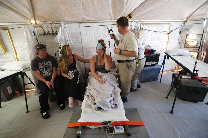 Aleeah Racette receives medical treatment inside the Florida 5 Disaster Medical Assistance Team tent, outside the Bay Medical Sacred Heart hospital, in the aftermath of Hurricane Michael in Mexico Beach, Fla., Thursday, Oct. 18, 2018. At left is her mother, Amy Cross, and Amy's fiance, Corey Shuman. (AP Photo/Gerald Herbert)