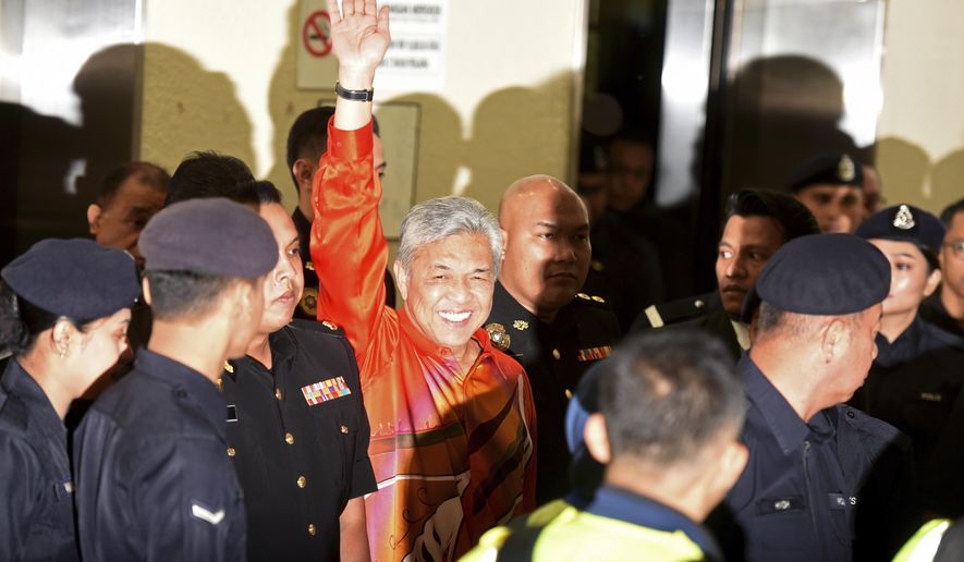 United Malays National Organization&#39;s (UMNO) Pexresident Ahmad Zahid Hamidi waves as he walks into courtroom at Kuala Lumpur High Court in Kuala Lumpur, Malaysia, Friday, Oct. 19, 2018. The anti-graft agency said Zahid was detained at its office shortly after he was summoned as part of its probe into abuse of power, criminal breach of trust and money laundering at a welfare group. It said in a statement that Zahid will be taken to court on Friday to face several charges under anti-corruption and anti-money laundering laws. (AP Photo/Yam G-Jun)
