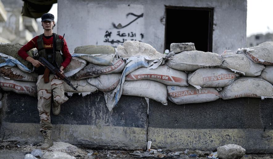 FILE - In this Oct. 13, 2018, file photo, a fighter of Syrian opposition stands at a checkpoint in northwestern city of Idlib, Syria. A Turkish official says Friday, Oct. 19, 2018, that a summit between the leaders of Turkey, France, Germany and Russia will be held in Istanbul this month to discuss the conflict in Syria. Presidential spokesman Ibrahim Kalin, in a written statement Friday said a summit will take place on Oct. 27. Russia and Turkey reached an agreement last month to set up a demilitarized zone around the northwestern Syrian province of Idlib preventing a government offensive on the last rebel stronghold in the country.(Ugur Can/DHA via AP, File)
