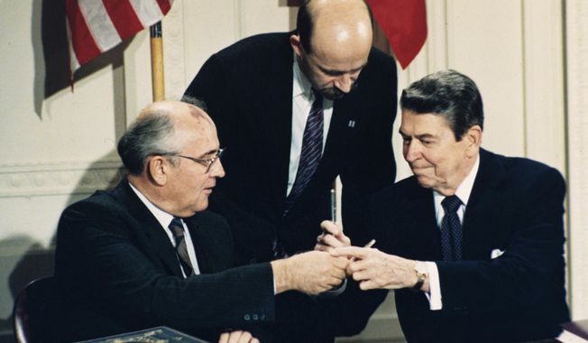 In this Dec. 8, 1987, file photo U.S. President Ronald Reagan, right, and Soviet leader Mikhail Gorbachev exchange pens during the Intermediate Range Nuclear Forces Treaty signing ceremony in the White House East Room in Washington, D.C. Gorbachev&#x27;s translator Pavel Palazhchenko stands in the middle. (AP Photo/Bob Daugherty, File)