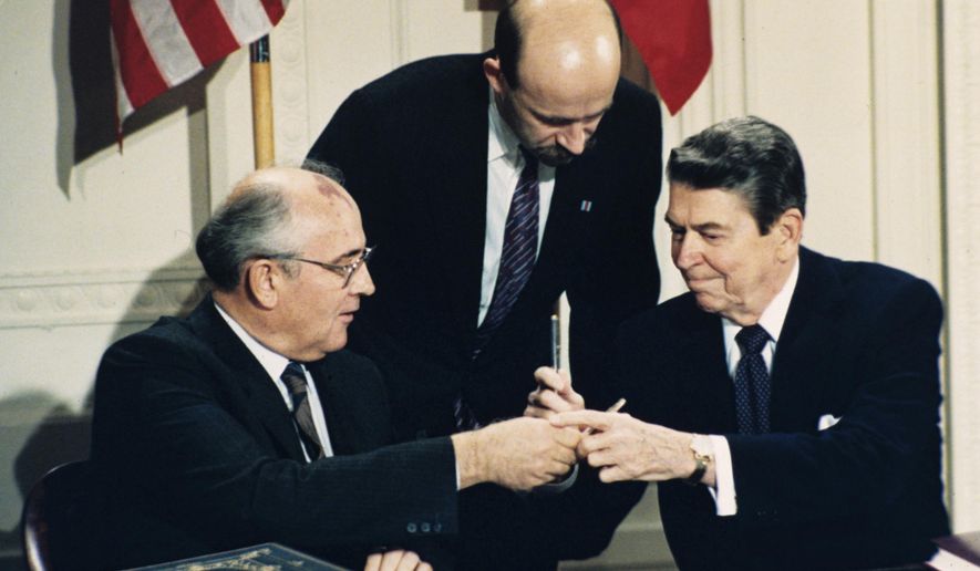 In this Dec. 8, 1987, file photo U.S. President Ronald Reagan, right, and Soviet leader Mikhail Gorbachev exchange pens during the Intermediate Range Nuclear Forces Treaty signing ceremony in the White House East Room in Washington, D.C. Gorbachev&#39;s translator Pavel Palazhchenko stands in the middle. (AP Photo/Bob Daugherty, File)