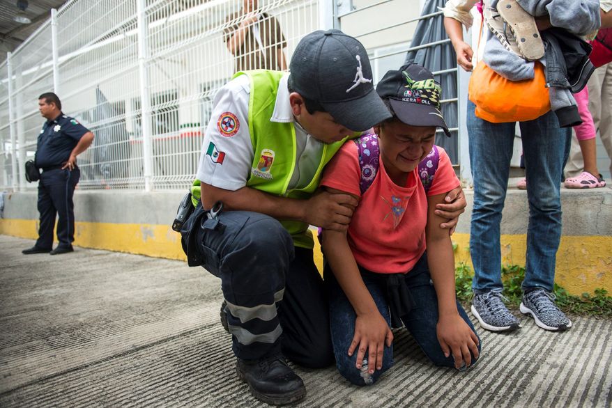 A migrant is comforted by a paramedic as the caravan of Central American migrants continues on a quest to reach the U.S. border. (Associated Press)