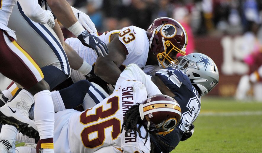 Dallas Cowboys running back Ezekiel Elliott (center) is tackled by Washington Redskins free safety D.J. Swearinger (bottom) and defensive end Jonathan Allen (top) during an NFL football game between the Dallas Cowboys and Washington Redskins, Sunday, Oct. 21, 2018, in Landover, Md. (AP Photo/Mark Tenally) **FILE**