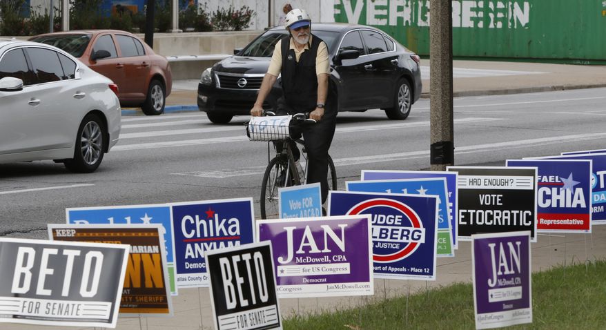 Gene Lantz rides pass candidates sign near the George L. Allen, Sr. Courts Building in Dallas on Monday, Oct. 22, 2018, on his way to a voting rally on the opening day of early voting across the State of Texas. Early voting starts Oct. 22 and ends Nov. 2. (Irwin Thompson/The Dallas Morning News via AP)