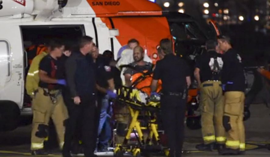 This Oct. 20, 2018 still photo taken from video provided by the United States Coast Guard shows a Coast Guard helicopter crew transferring one of two patients to emergency medical services personnel in San Diego, Calif. Coast Guard officials say three people are missing and 15 people were rescued Saturday, Oct. 20, 2018 after their fishing boat caught fire south of San Diego. (Petty Officer 1st Class Patrick Kelley/United States Coast Guard via AP)