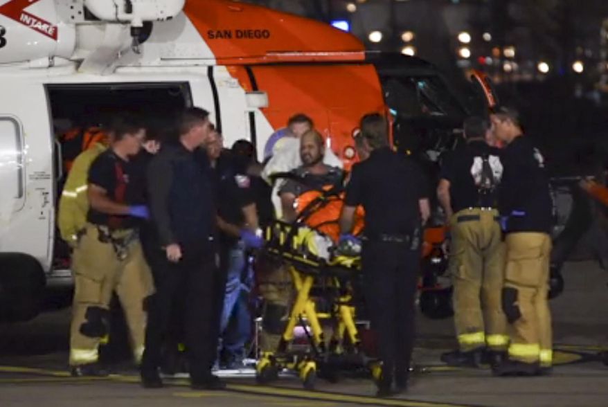 This Oct. 20, 2018 still photo taken from video provided by the United States Coast Guard shows a Coast Guard helicopter crew transferring one of two patients to emergency medical services personnel in San Diego, Calif. Coast Guard officials say three people are missing and 15 people were rescued Saturday, Oct. 20, 2018 after their fishing boat caught fire south of San Diego. (Petty Officer 1st Class Patrick Kelley/United States Coast Guard via AP)