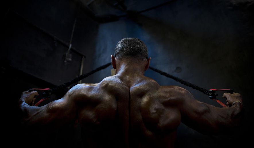 In this Thursday, Oct. 18, 2018 photo, a contestant exercises backstage during the National Amateur Body Builders&#39; Association competition in Tel Aviv, Israel. Dozens of glistening competitors took the stage for the annual body building and fitness competition last week. But behind the scenes, machismo makes way for cooperation. (AP Photo/Oded Balilty)