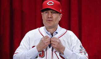 Cincinnati Reds manager David Bell puts on his number 25 jersey during a news conference, Monday, Oct. 22, 2018, in Cincinnati. Bell has been hired as manager of the Cincinnati Reds, tasked with helping turn around a team that skidded to a 67-95 record and last-place finish in the NL Central. The Reds said Sunday, Oct. 21, 2018, he has been given a three-year contract that includes a team option for 2022. (AP Photo/John Minchillo)