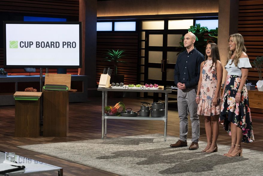 In this image provided by ABC, Kevin Young’s children present the product of their late father, Cup Board Pro, which is a chopping block that features a detachable bowl for clean up, on a "Shark Tank" episode that aired on Sunday, Oct. 21, 2018. The sharks on “Shark Tank” are supporting the invention created by a New York City firefighter who died of cancer after helping with the cleanup of ground zero following the Sept. 11 terrorist attacks. (Eric McCandless/ABC via AP)