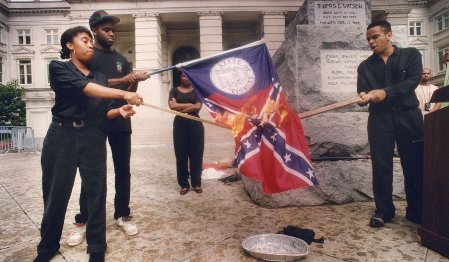 In this June 1992 photo, from left, Ina Solomon, Jeffery Harris, Stacey Abrams and Lawrence Jeffries burn a Georgia state flag during a demonstration at the state Capitol in Atlanta. Jeffries, at the time, described the act as burning Georgia&#x27;s &quot;racist past&quot;. The campaign of Democratic candidate for Georgia governor Stacey Abrams is defending her involvement in burning the state flag more than 25 years ago. At the time it contained a prominent Confederate symbol.  (W.A. Bridges Jr./Atlanta Journal-Constitution via AP)