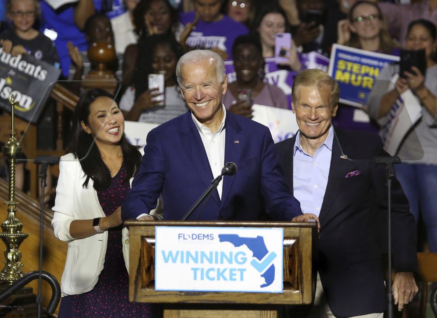 Rep. Stephanie Murphy, former Vice President Joe Biden and Sen. Bill Nelson respond to cheering supporters as Biden headlined a rally for Democrats in downtown Orlando, Fla., Tuesday, Oct. 23, 2018. Floridians go to the polls for the midterm election in two weeks. (Joe Burbank/Orlando Sentinel via AP)