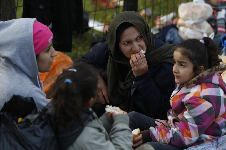 Migrants eat after having camped near a police barricade at a border crossing in Izacici near Bihac, on Bosnia's border with Croatia, Tuesday, Oct. 23, 2018. Several dozen migrants, including children, have spent the night out in the open near Bosnia’s border with Croatia after walking for some 15 kilometers (9 miles) to draw attention to their plight and the fact that borders remain closed for people trying to reach Western Europe. (AP Photo/Amel Emric)