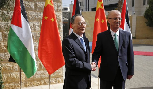 Chinese Vice President Wang Qishan shakes hands with Palestinian Prime Minister Rami Hamdallah in the West Bank city of Ramallah, Tuesday, Oct. 12, 2018 2018. (Abbas Momani/Pool via AP)