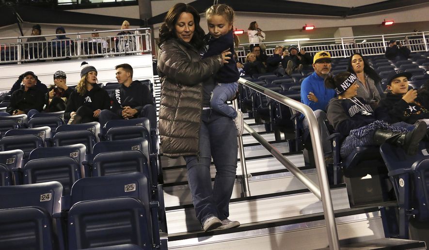 In this Oct. 13, 2018 photo, Ella Marini, 7, gets carried by her mother, Jen, to her seat in Mackay Stadium to see an NCAA college football game between Nevada and Boise State in Reno, Nev. The University of Nevada, Reno, plans to spend $2 million on top of nearly $700,000 spent last year to fix accessibility mistakes following a $14 million Mackay Stadium upgrade in 2016. (Jason Bean/The Reno Gazette-Journal via AP)