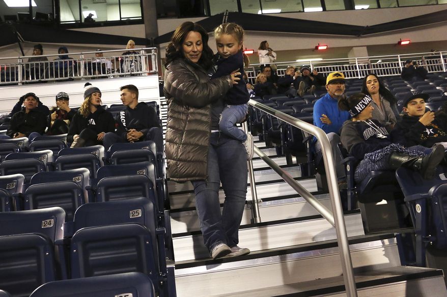 In this Oct. 13, 2018 photo, Ella Marini, 7, gets carried by her mother, Jen, to her seat in Mackay Stadium to see an NCAA college football game between Nevada and Boise State in Reno, Nev. The University of Nevada, Reno, plans to spend $2 million on top of nearly $700,000 spent last year to fix accessibility mistakes following a $14 million Mackay Stadium upgrade in 2016. (Jason Bean/The Reno Gazette-Journal via AP)