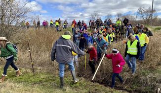 Volunteers cross a creek and barbed wire near Barron, Wis., Tuesday, Oct. 23, 2018, on their way to a ground search for 13-year-old Jayme Closs who was discovered missing Oct. 15 after her parents were found fatally shot at their home. The search for Closs was expanded Tuesday, with as many as 2,000 volunteers expected to take part in a search of the area. (AP Photo/Jeff Baenen)