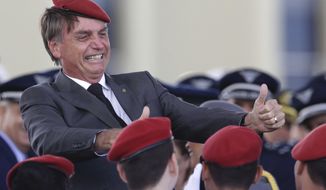 FILE - In this April 19, 2018 file photo, presidential hopeful, conservative Brazilian lawmaker Jair Bolsonaro flashes two thumbs up as he poses for a photo with cadets during a ceremony marking Army Day, in Brasilia, Brazil. As Sunday’s, Oct. 28 election approaches, fierce debates are unfolding in Brazil and beyond over how to describe Bolsonaro, a candidate whose eclectic mix of policies and harsh language thrills supporters and terrifies detractors. (AP Photo/Eraldo Peres, File)