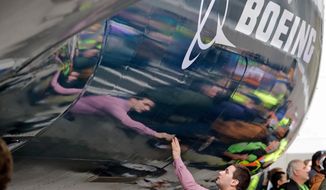 FILE - In this Feb. 5, 2018, file photo, Boeing worker Paul Covaci reaches out to touch a Boeing 737 MAX 7, the newest version of Boeing&#39;s fastest-selling airplane, during a debut for employees and media of the new jet in Renton, Wash. Boeing Co. reports earnings Wednesday, Oct. 24. (AP Photo/Elaine Thompson, File)
