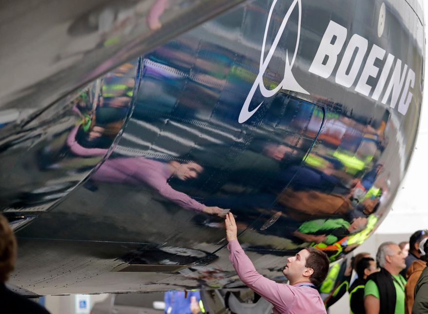 FILE - In this Feb. 5, 2018, file photo, Boeing worker Paul Covaci reaches out to touch a Boeing 737 MAX 7, the newest version of Boeing&#x27;s fastest-selling airplane, during a debut for employees and media of the new jet in Renton, Wash. Boeing Co. reports earnings Wednesday, Oct. 24. (AP Photo/Elaine Thompson, File)