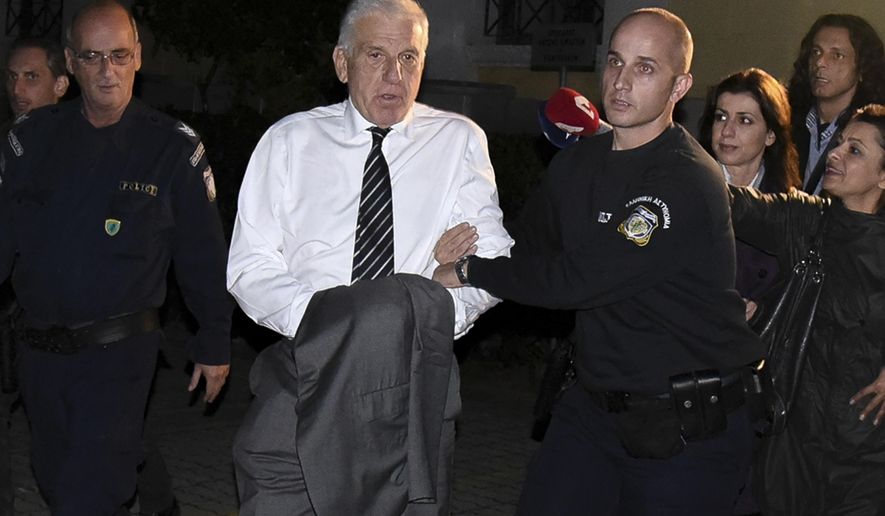 In this Tuesday, Oct. 23, 2018 photo, former Greek finance minister Yannos Papantoniou is escorted by policemen to a police van at a court in Athens. Papantoniou, who headed the country's effort to join the euro, and will be held in pre-trial detention in Athens from Wednesday, Oct. 24, 2018, on money laundering charges stemming from bribes allegedly paid to secure a 2003 navy contract. (Yannis Liakos/InTime News via AP)
