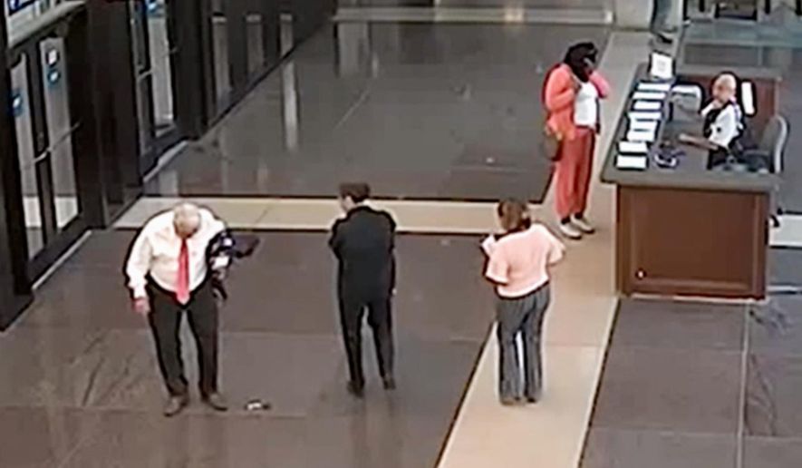 FILE - In this July 3, 2018, file photo from a surveillance video provided by the Cook County Sheriff's Office, Cook County Circuit Judge Joseph Claps, left, looks down at an object he allegedly dropped in the lobby of the Leighton Criminal Court Building in Chicago. Claps was charged with carrying a concealed weapon in a prohibited area. On Tuesday, Oct. 23, 2018, Claps was acquitted after a judge ruled the video did not prove the object that fell from Claps' jacket was a firearm. (Cook County Sheriff's Office via AP, File)