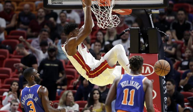 Miami Heat center Hassan Whiteside dunks over New York Knicks guard Tim Hardaway Jr. (3) and guard Frank Ntilikina (11) during the first half of an NBA basketball game, Wednesday, Oct. 24, 2018, in Miami. (AP Photo/Lynne Sladky)