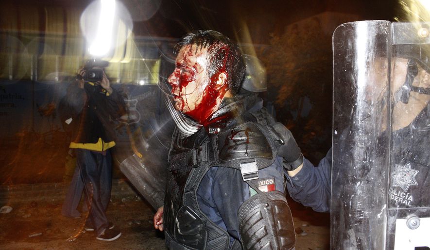 This Oct. 2012 handout photo provided by Gustavo Aguado shows a bloodied federal police officer injured during an eviction of students, in Tiripetio, Mexico. This photo was not taken in confrontations with migrants making their way in a caravan from Central America to the U.S., despite a post circulating on social media. (Photo by Gustavo Aguado via AP)